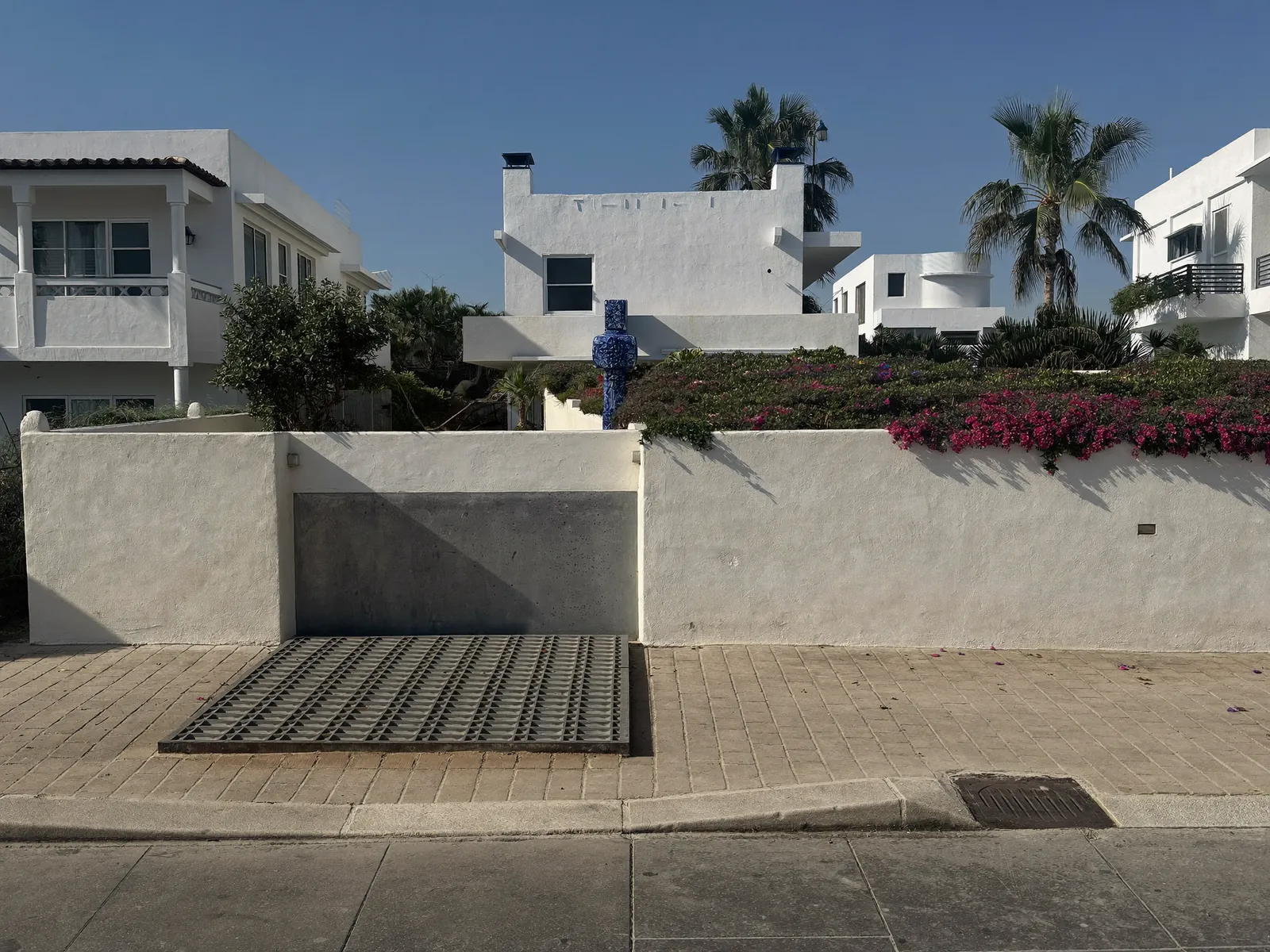 Classic low white villa in Jumeirah, Dubai, behind a garden wall with bougainvillea