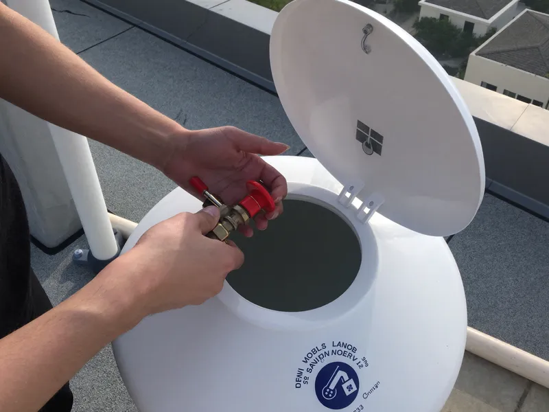 Plumber replacing a brass float valve inside a villa roof water tank in Dubai